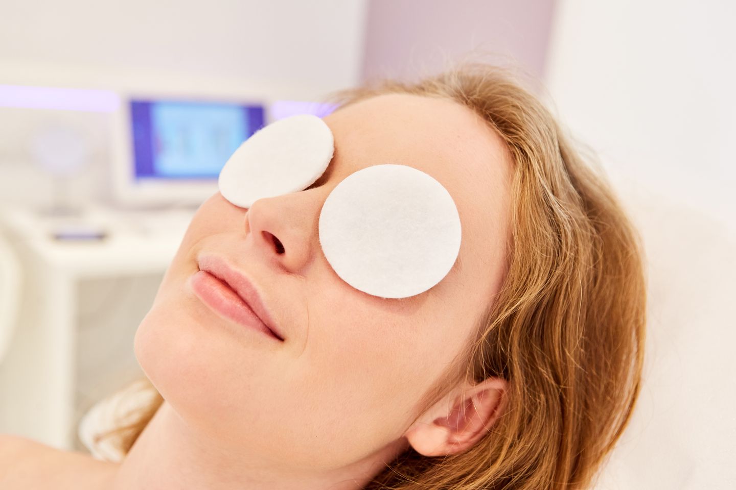 woman relaxing with cotton pads on eyes during eyelid skincare treatment