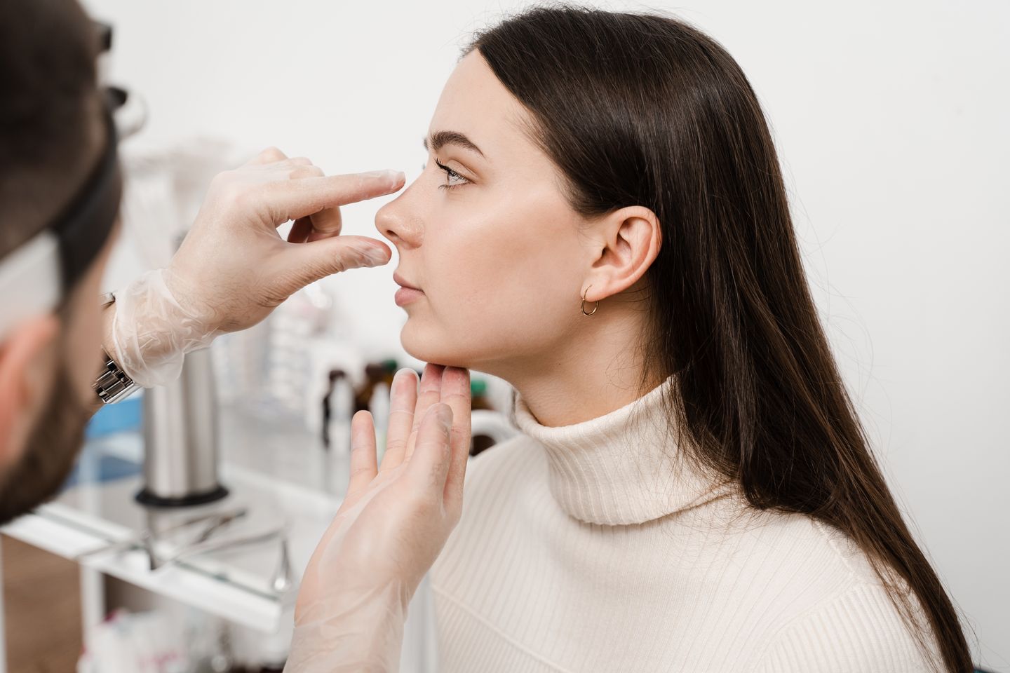 surgeon examining patient nose during rhinoplasty consultation