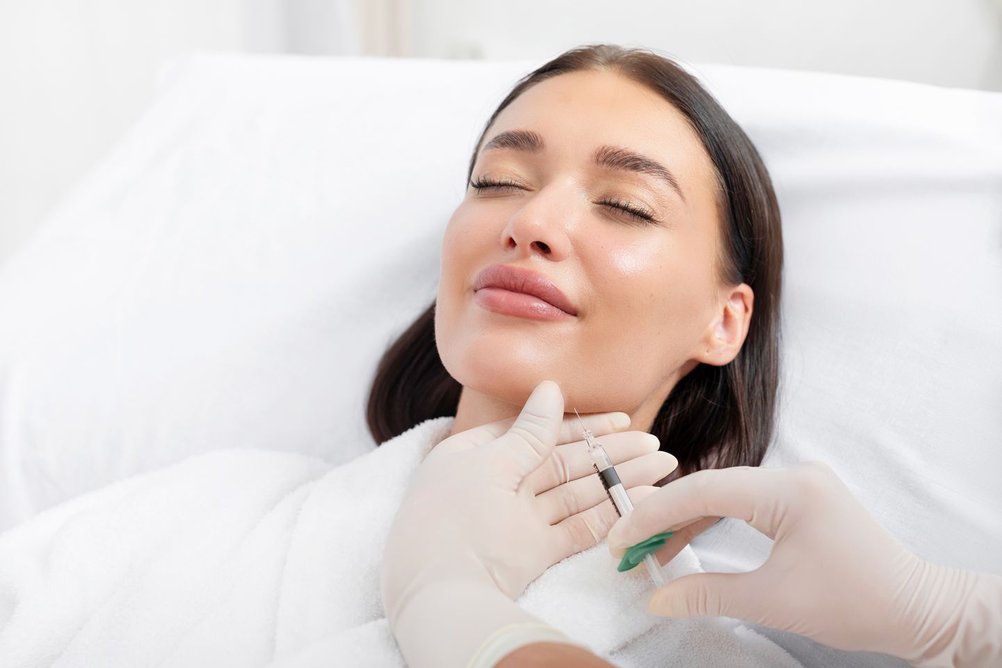 Cosmetologist injecting under the chin to reduce submental fullness