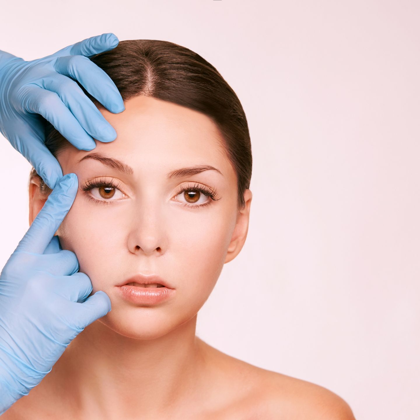 Doctor in gloves examining a woman forehead during a pre-op consultation