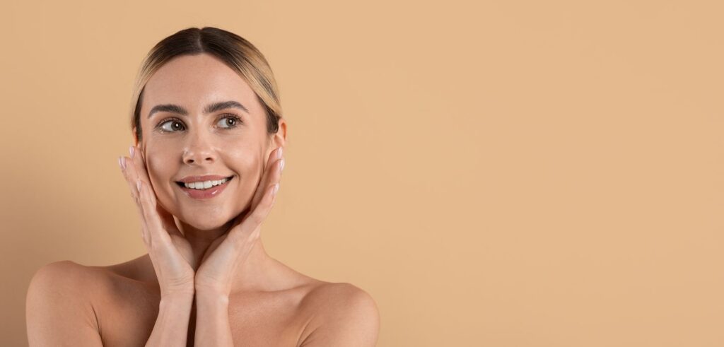 Beautiful young woman with healthy, glowing skin touching her face