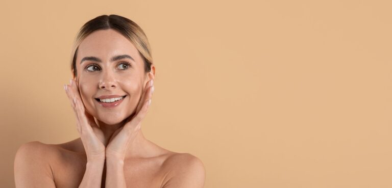 Beautiful young woman with healthy, glowing skin touching her face